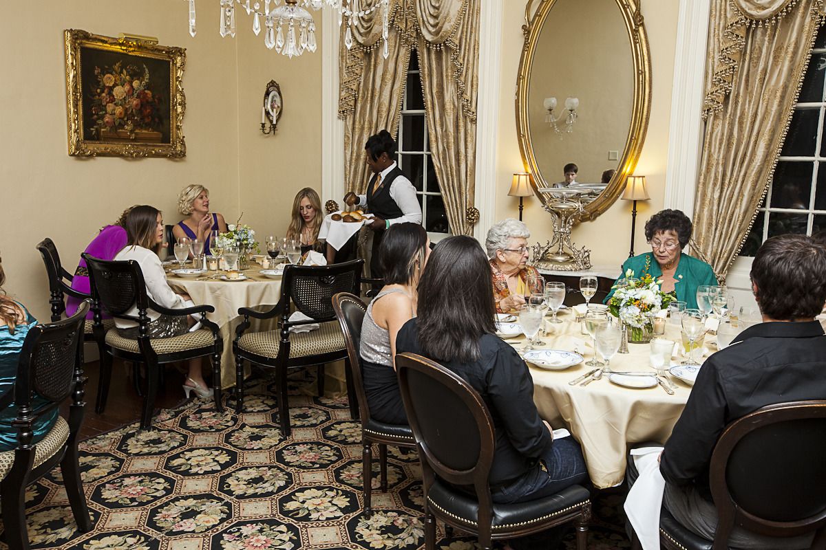 Une salle à manger élégante, dotée d’une décoration raffinée, comprenant un grand miroir, des lustres et une moquette à motifs.