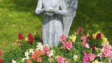 A garden statue of an angel surrounded by a variety of colorful flowers.