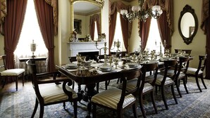 Comedor formal con una larga mesa dispuesta para una comida, rodeada de sillas tapizadas.
