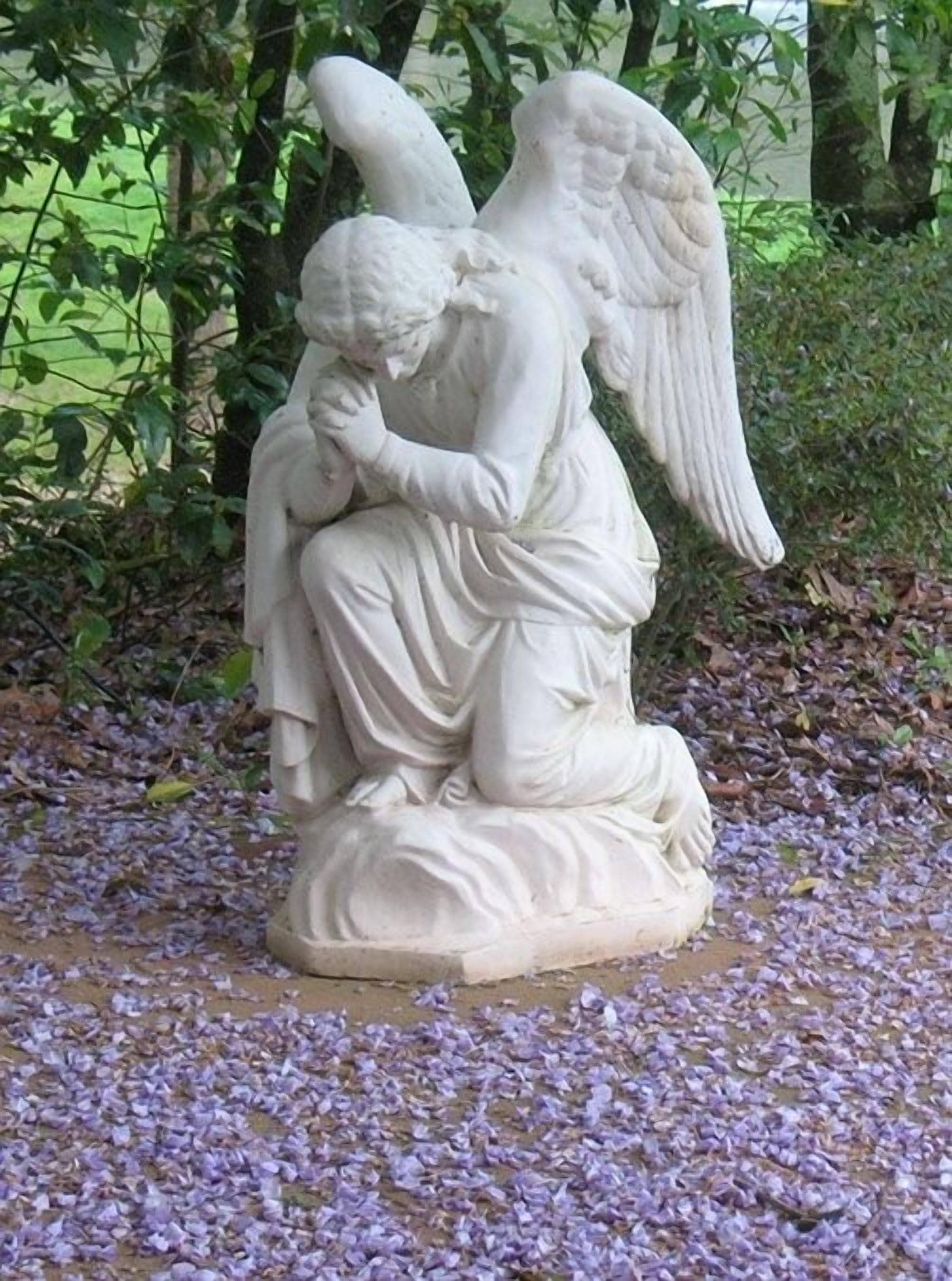 A statue of an angel kneeling and embracing a child.