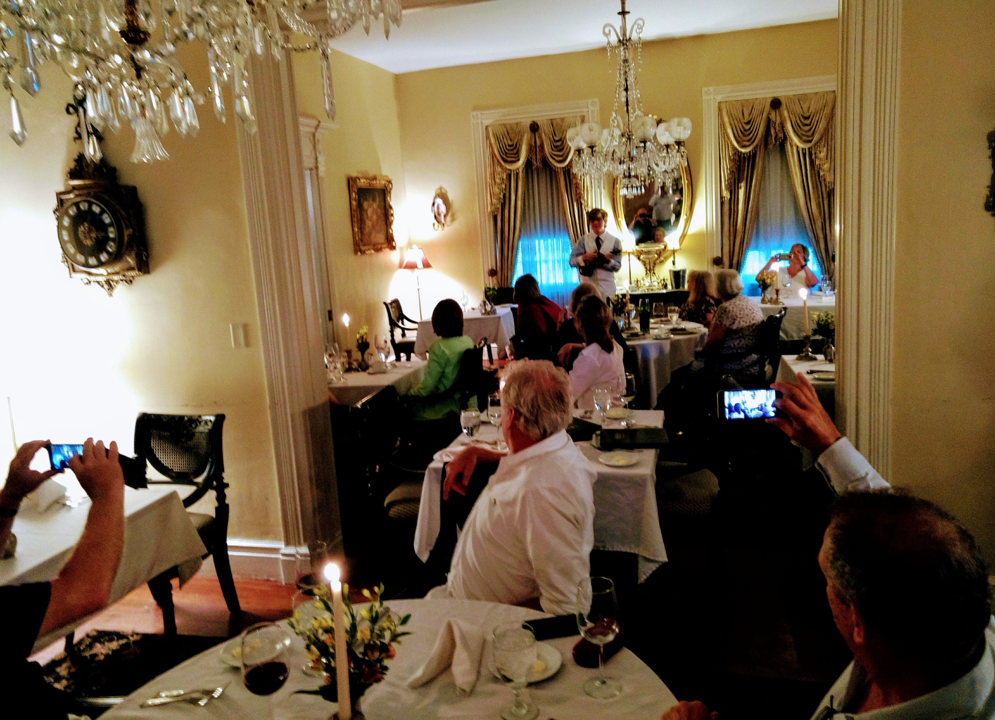 Un comedor formal con candelabros, cortinas ornamentadas y un reloj en la pared.
