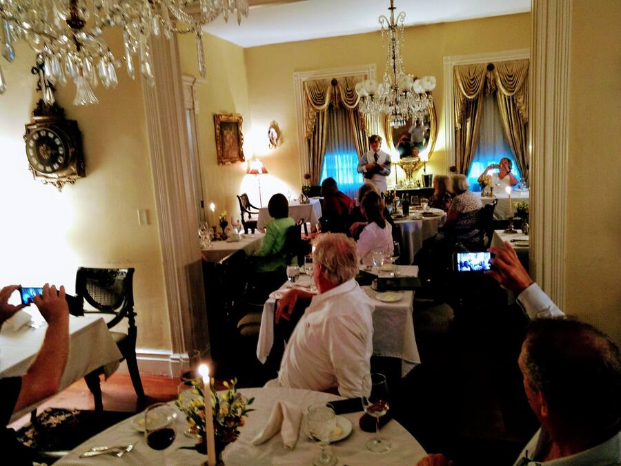 Un comedor formal con candelabros, cortinas ornamentadas y un reloj en la pared.
