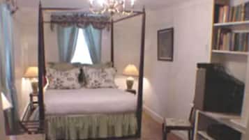 A four-poster bed with a canopy, two bedside lamps, a bookshelf, and a television on a stand.