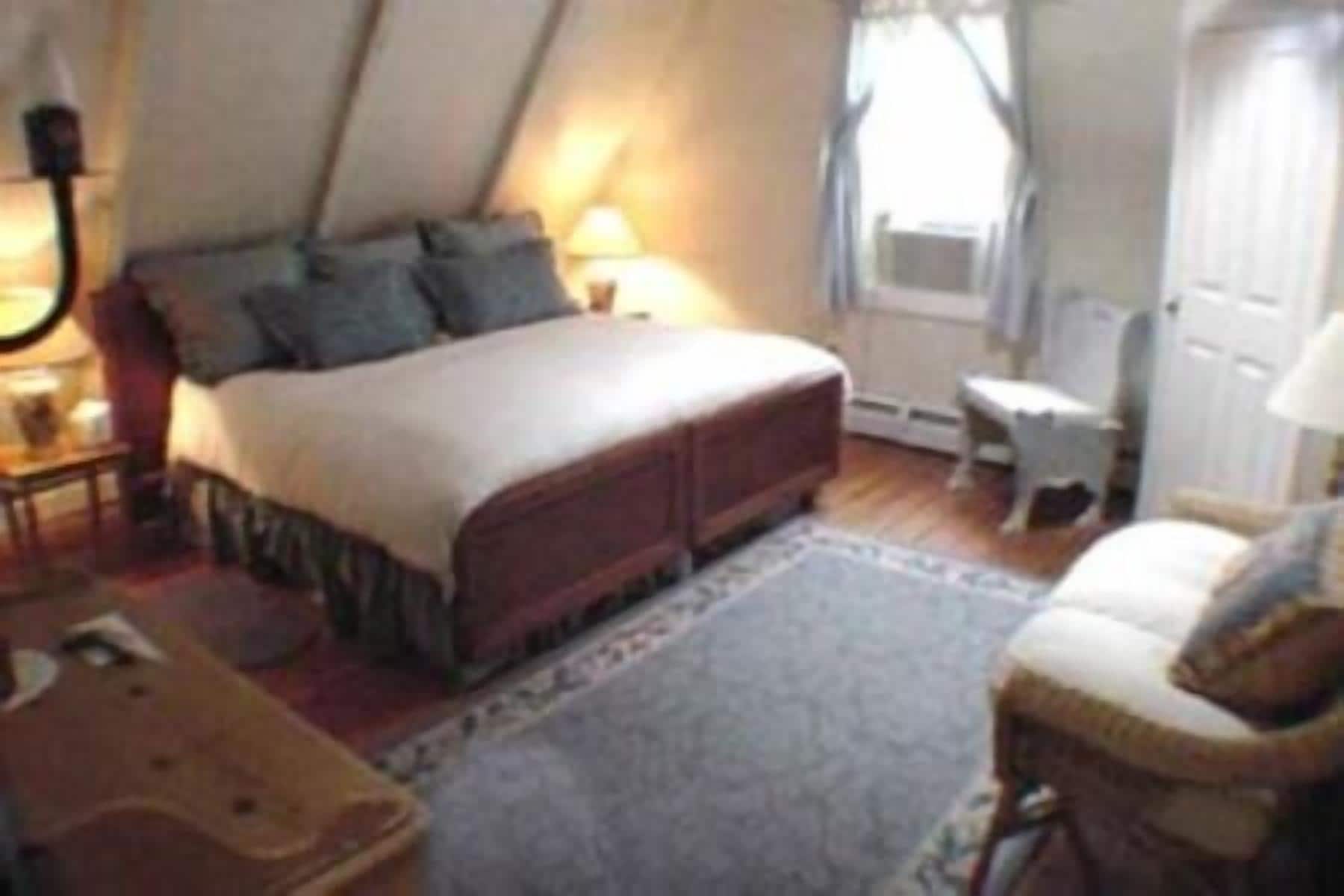 A bedroom with a bed, bedside tables, a chair, and a window.