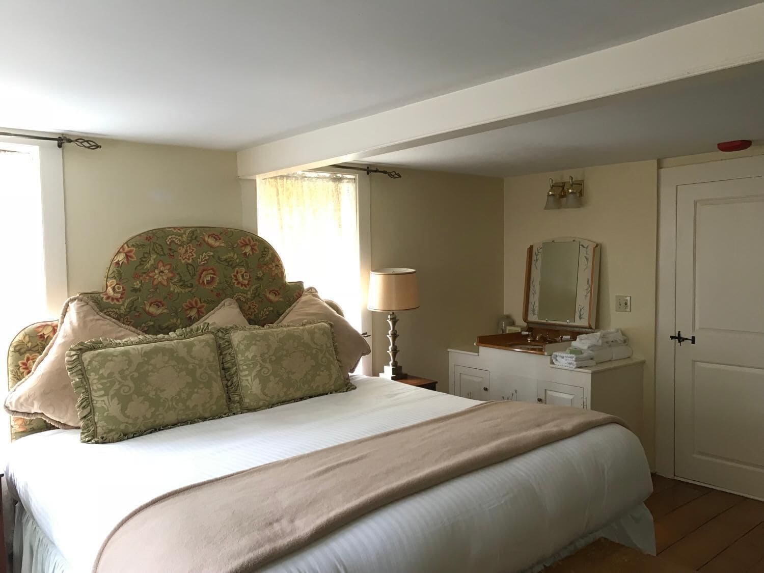 A bedroom with a bed, a dresser, a mirror, and a door.