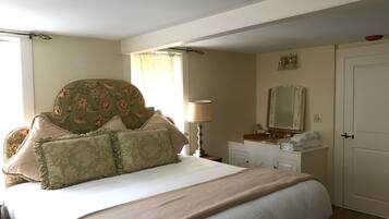 A bedroom with a bed, a dresser, a mirror, and a door.