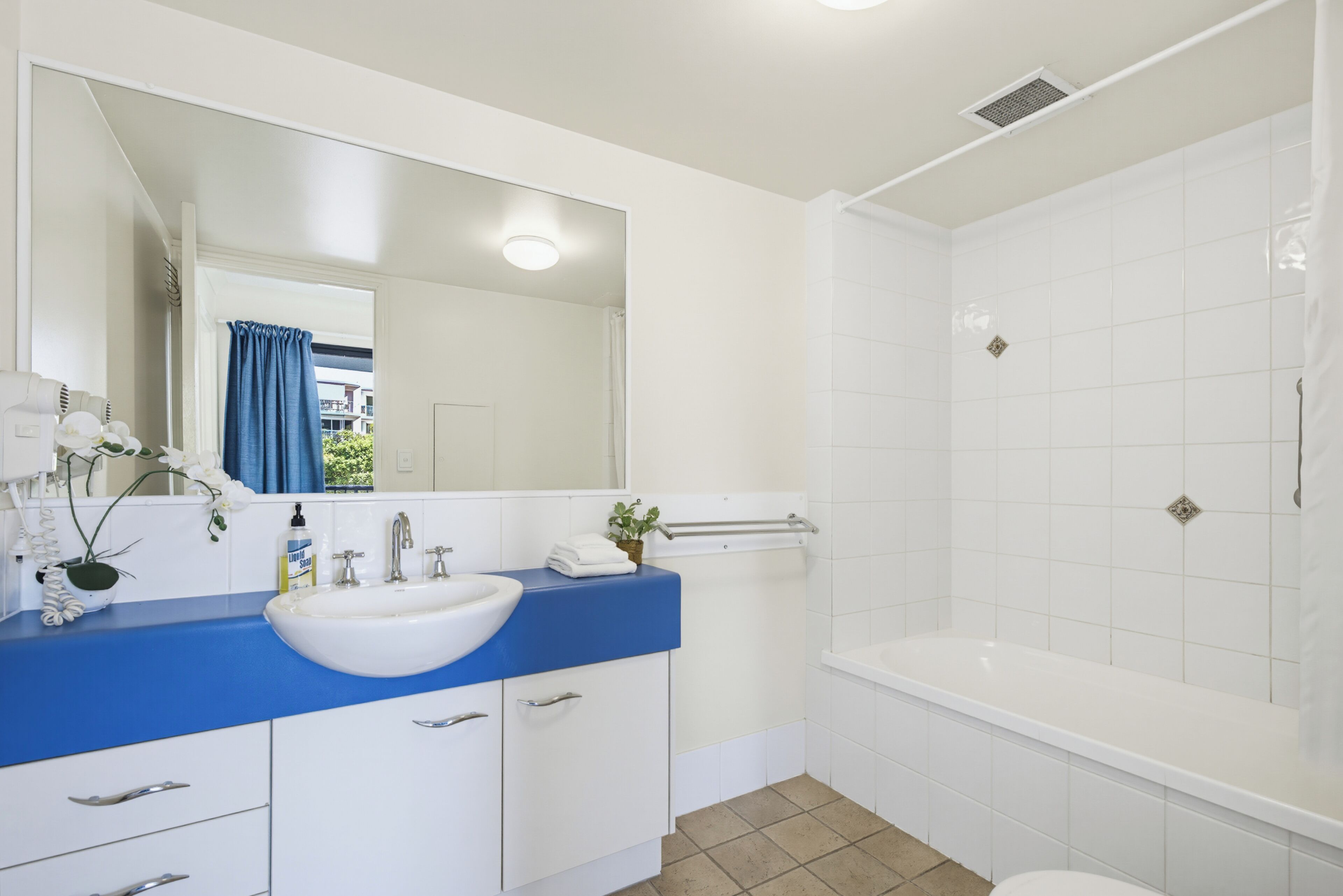 A modern bathroom with a white sink, blue countertop, and a separate shower area.
