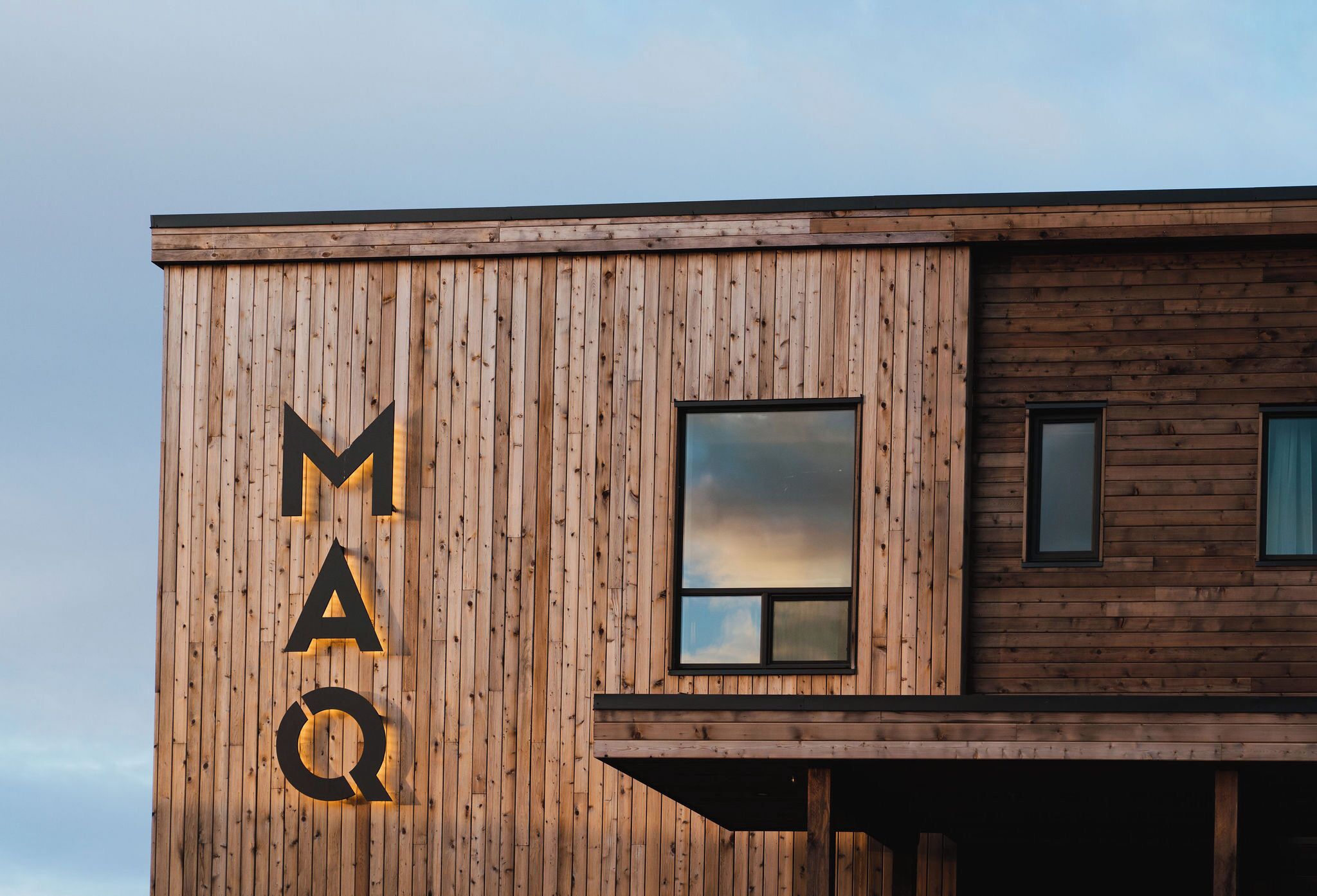 Un bâtiment doté d’une façade en bois sur laquelle les lettres « MAQ » sont clairement visibles.