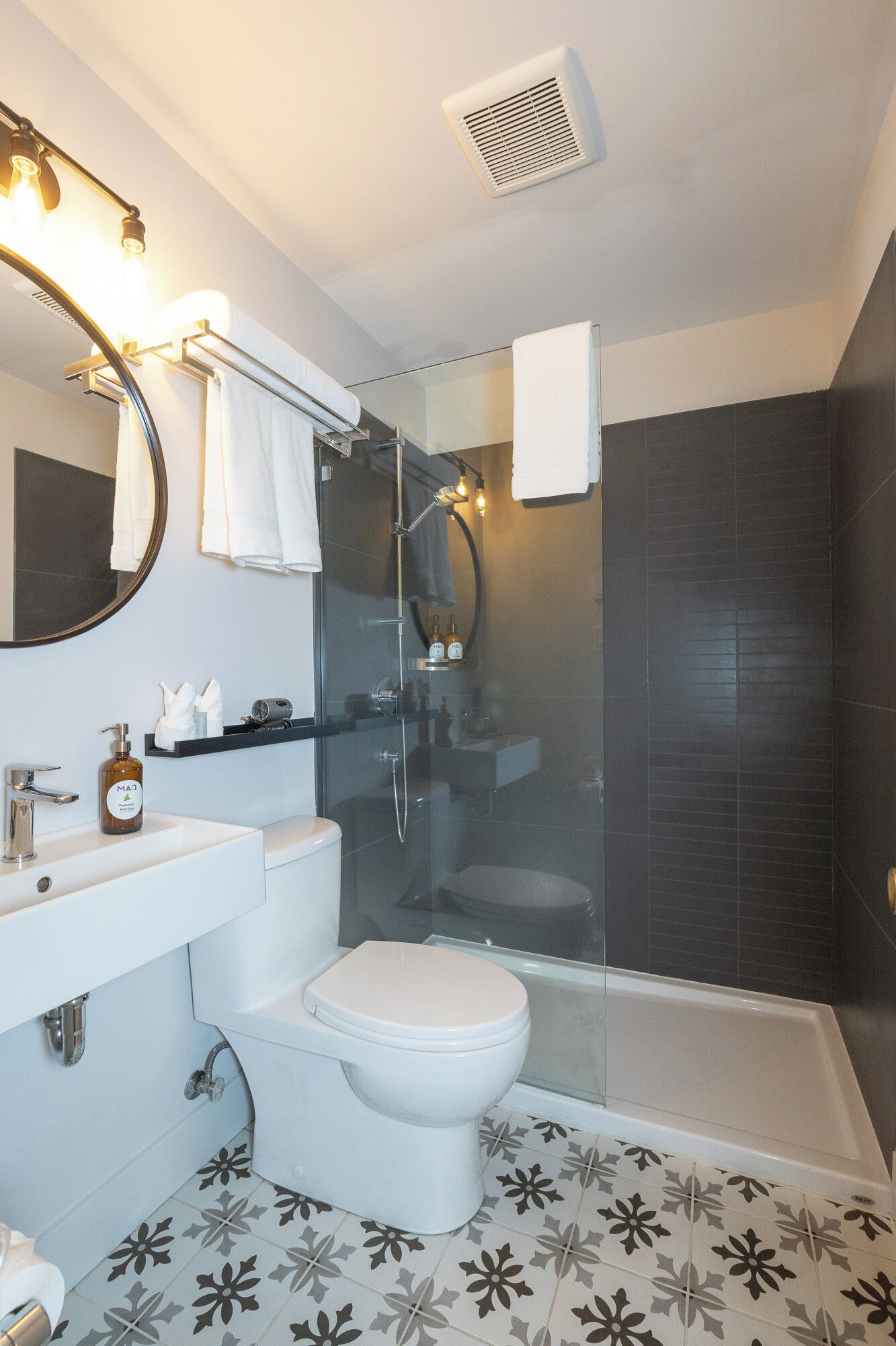A modern bathroom with a glass-enclosed shower, a white toilet, a sink with a mirror, and a towel rack.