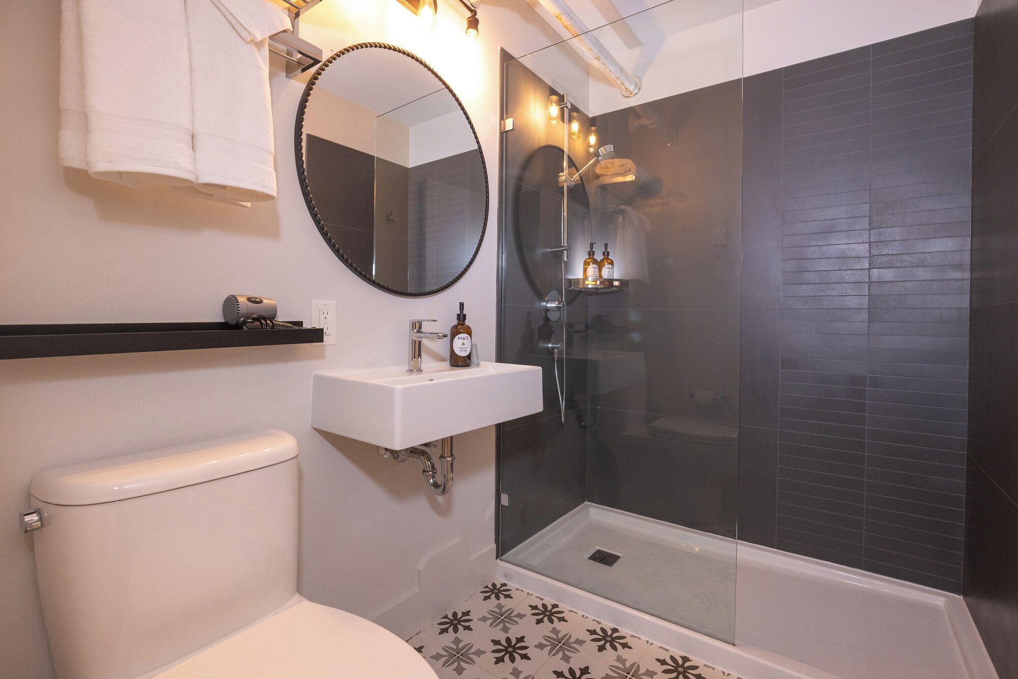 A modern bathroom with a toilet, a sink, a mirror, and a glass-enclosed shower area.