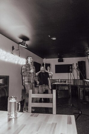 A room with a neon sign, a table with a glass, and a microphone stand. - The Maq Hotel (Tofino)