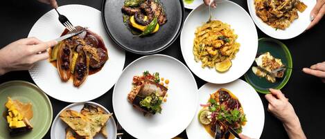 A variety of dishes on plates with people eating.