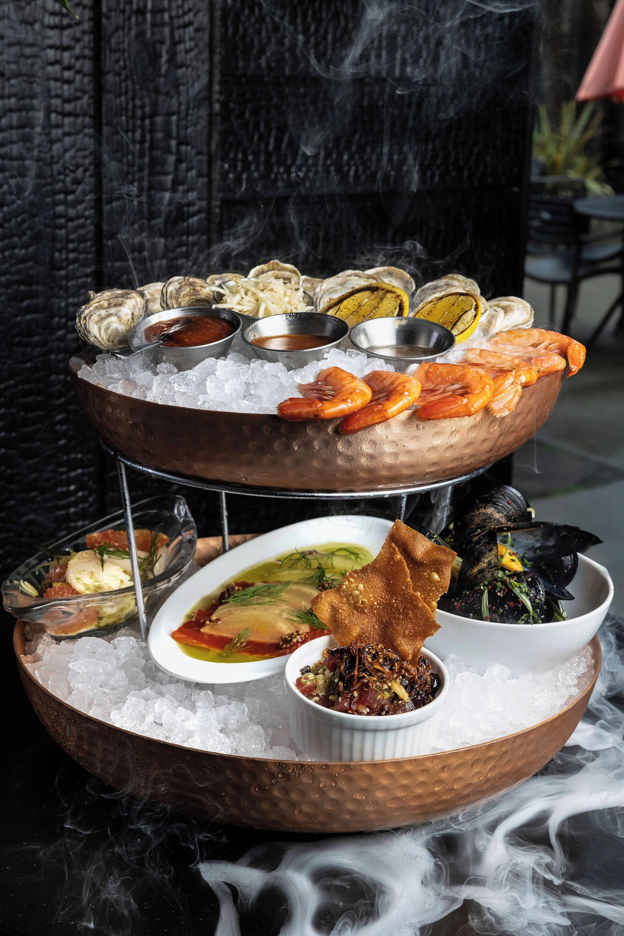 A multi-tiered seafood display with various dishes on ice.