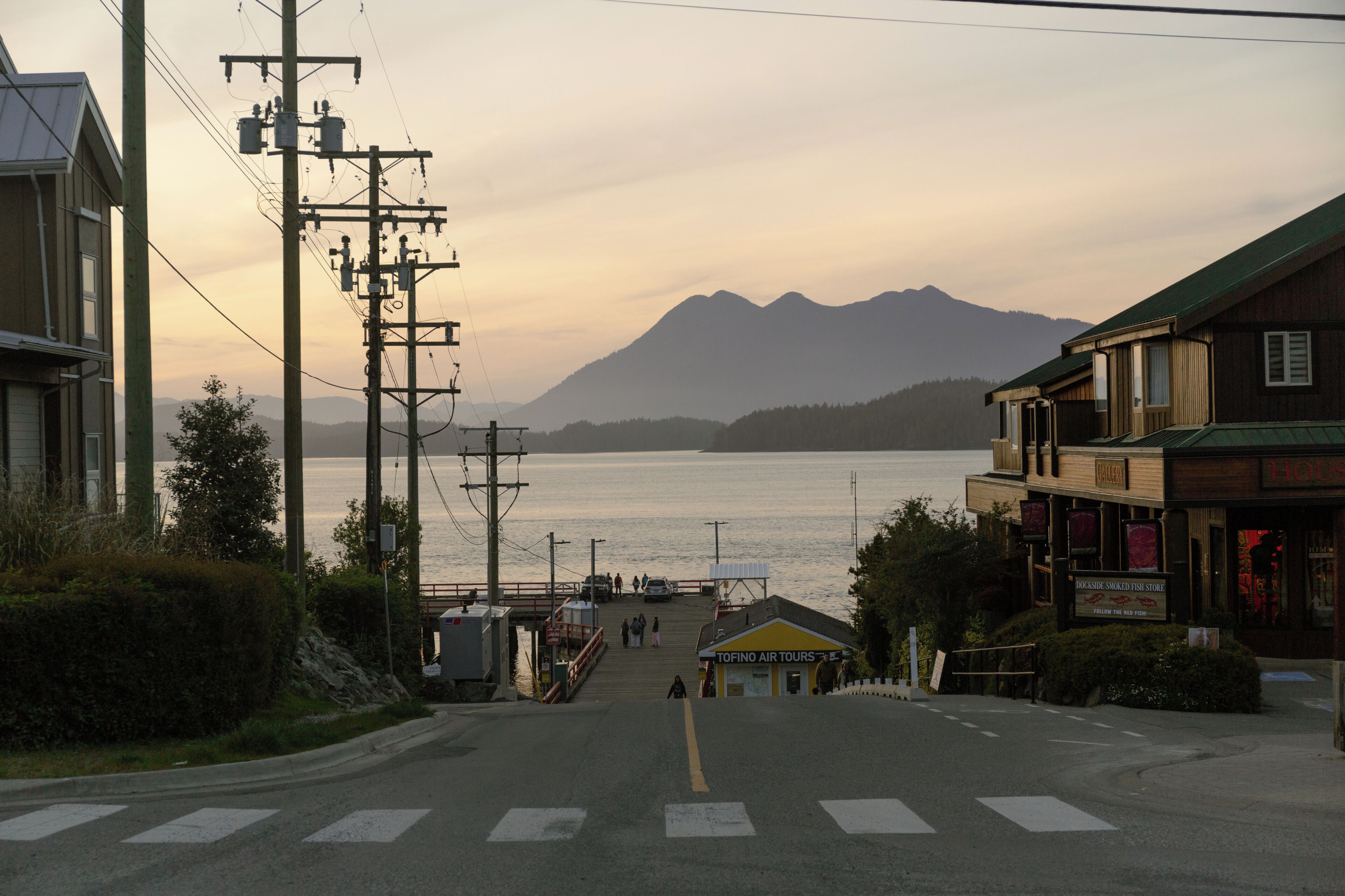 Une rue bordée de quais, avec des bâtiments et des montagnes en arrière-plan.