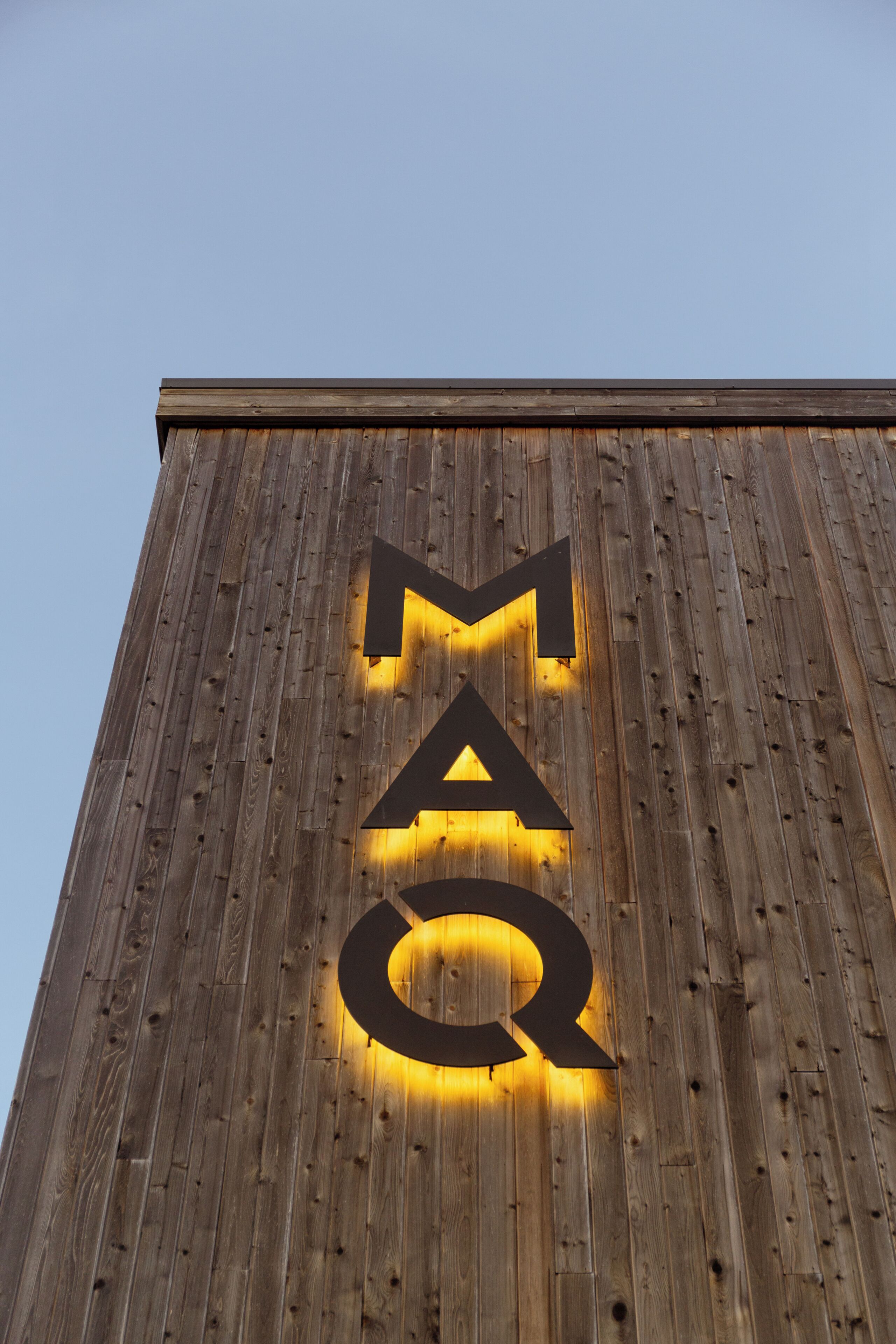 A wooden wall with illuminated letters spelling 'MAQ'.