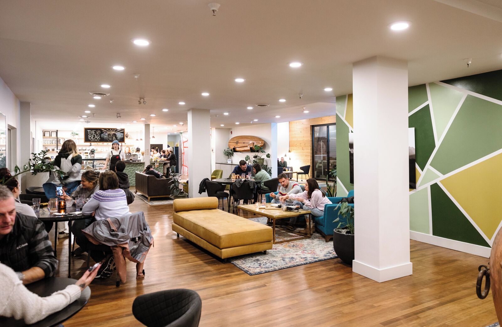 A modern interior with seating areas, a bar, and a kitchen visible in the background.