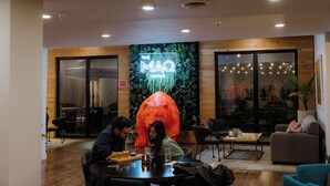Interior de restaurante con un letrero de neón, paneles de madera y una gran escultura naranja.