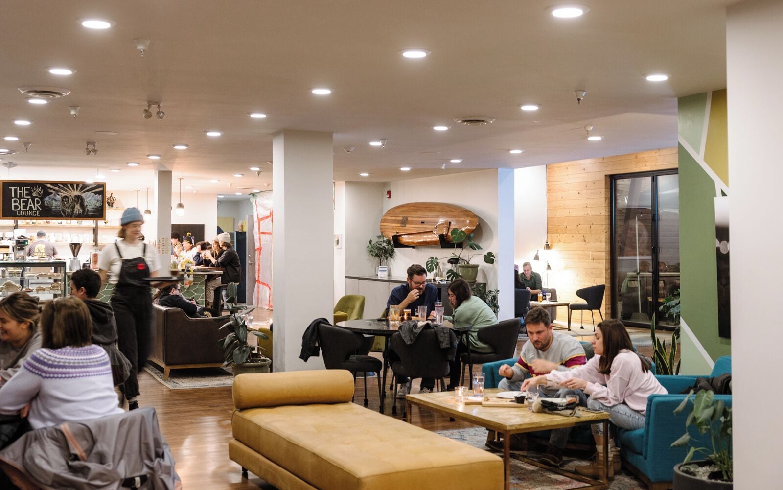 Un interior de cafetería moderno con mesas redondas, asientos cómodos y una zona de bar.