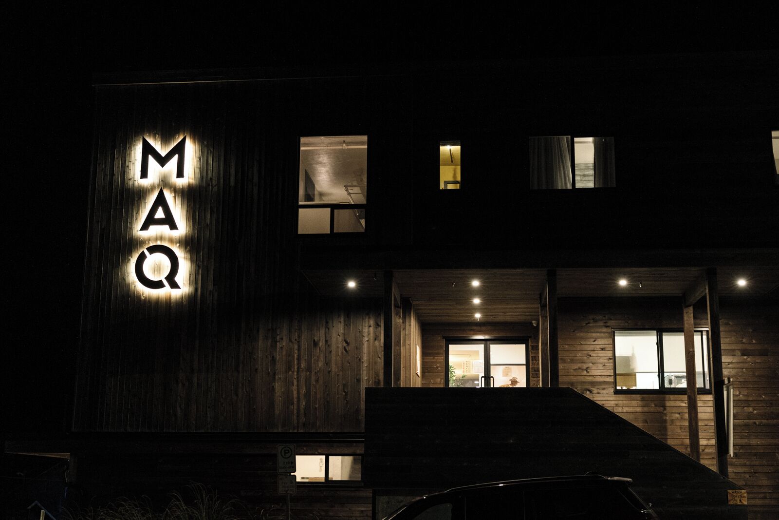 A building with a prominent illuminated sign reading 'MAQ' on the facade.