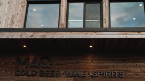 Fachada de edificio con un letrero que dice 'MAQ GOLD BEER WINE SPIRITS'.