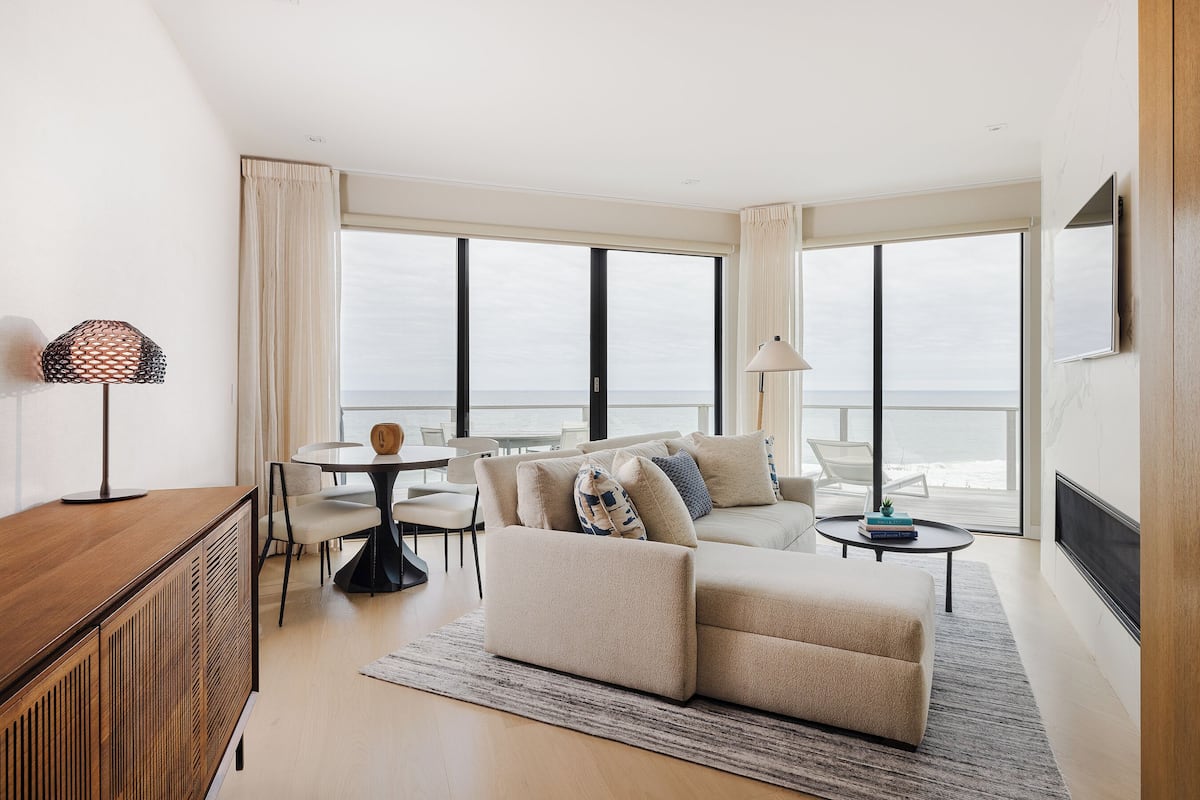 A modern living room with a sofa, a dining table, and a TV.