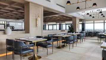 Ein geräumiges Restaurant mit hohen Decken, moderner Beleuchtung und großen Fenstern mit Aussicht.