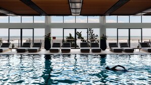 An indoor swimming pool with a view of the beach, lounge chairs, and large windows. - Gurney's Montauk Resort & Seawater Spa (Montauk)