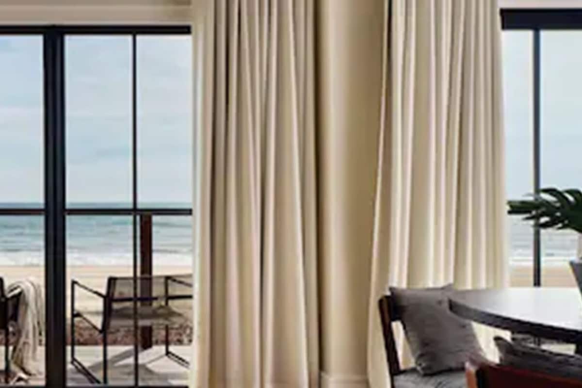 A room with a large sliding glass door leading to a beach view.
