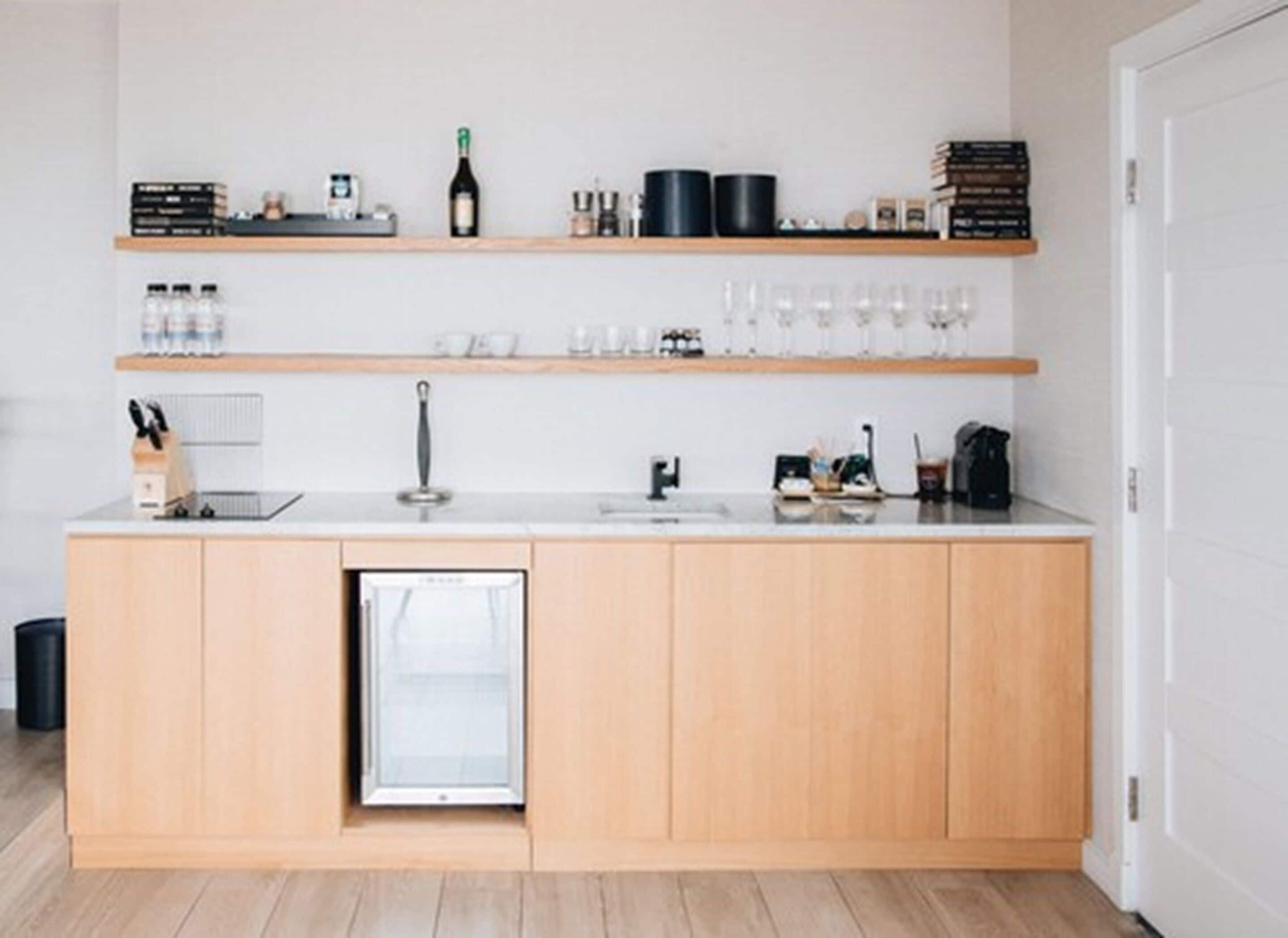 Une cuisine moderne avec des meubles de rangement en bois, un lave-vaisselle encastré et des étagères où sont rangés les ustensiles de cuisine et les bouteilles.