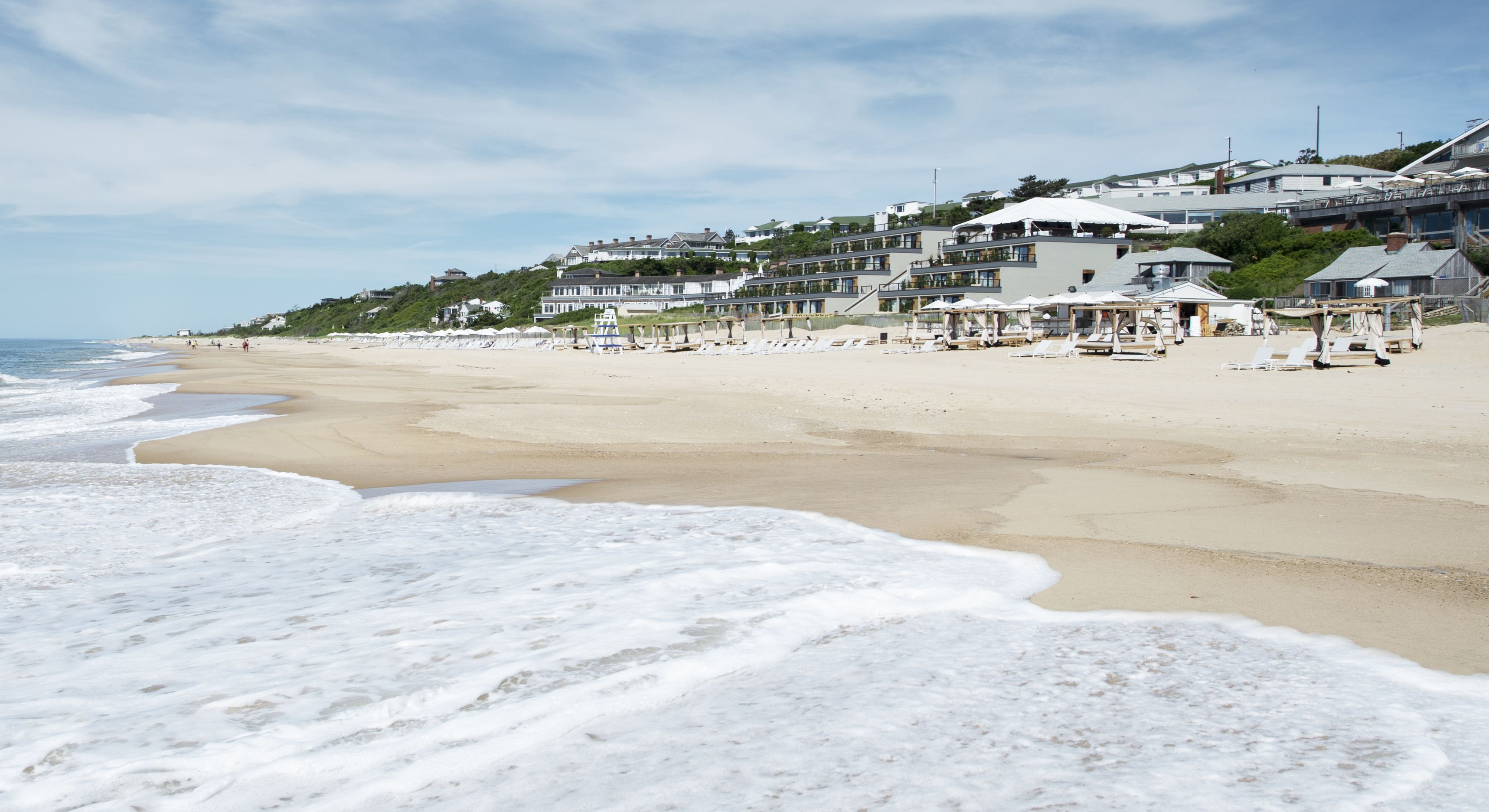 Een strand met een rij strandhuizen en een heldere lucht.