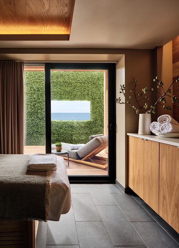 Une chambre moderne dotée d’une porte-fenêtre coulissante donnant sur un balcon avec vue sur la mer.
