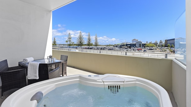 Un balcón con jacuzzi, mobiliario exterior y vistas a un paisaje urbano.
