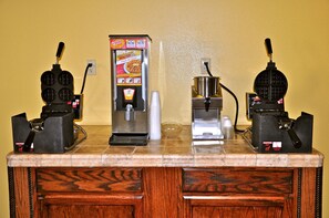 A kitchen counter with two waffle makers, a waffle maker, and a coffee maker.