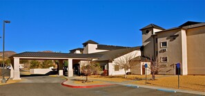 A building with a covered entrance, a parking lot, and a sign indicating handicapped parking.