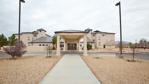 A building with a covered entrance, a gravel driveway, and a clear sky.