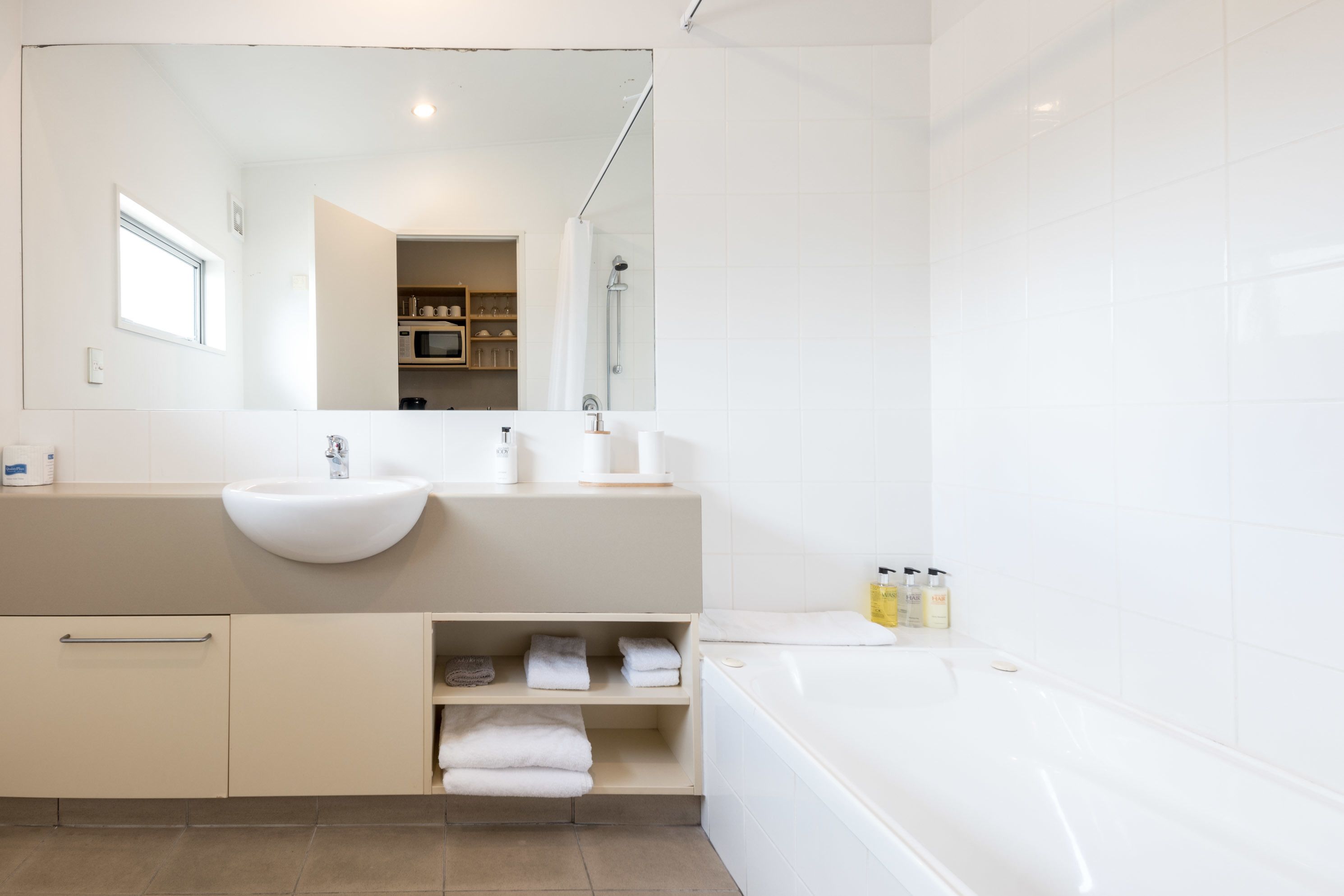 A modern bathroom with a large sink, a bathtub, and a mirror.