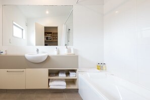 A modern bathroom with a large sink, a bathtub, and a mirror. - The Westhaven Motel (Fox Glacier)