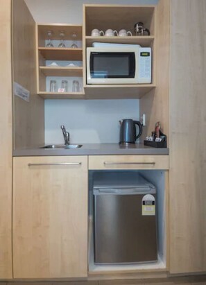 A compact kitchen with a microwave, a kettle, and a small refrigerator. - The Westhaven Motel (Fox Glacier)