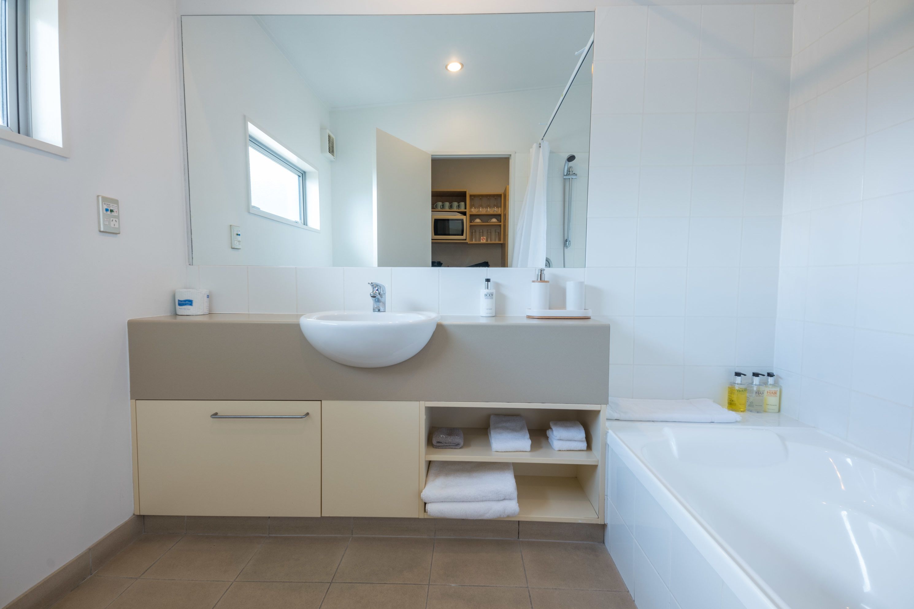 Un baño moderno con un lavamanos grande, espejo y bañera.