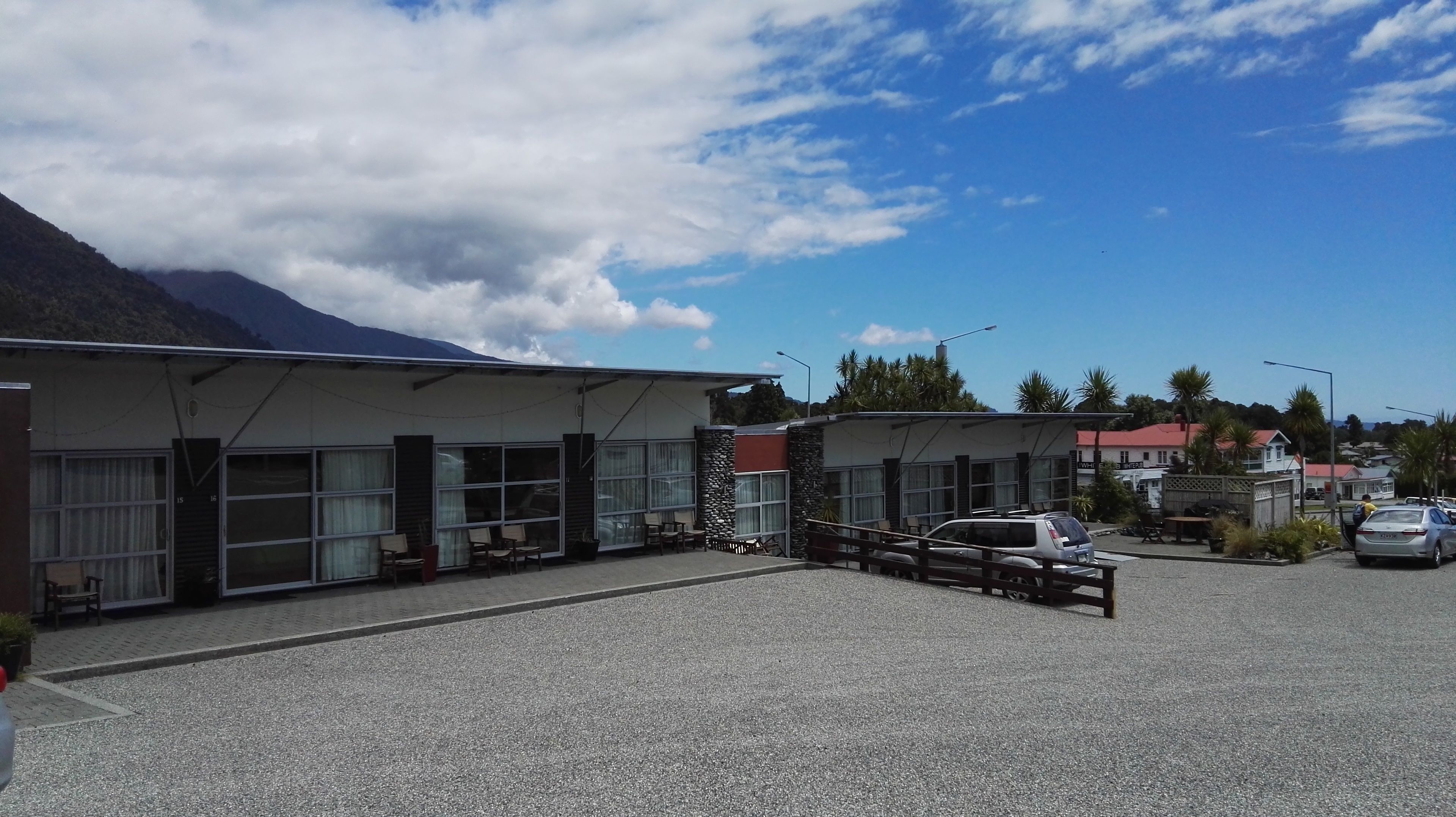A building with large windows and a gravel parking area.