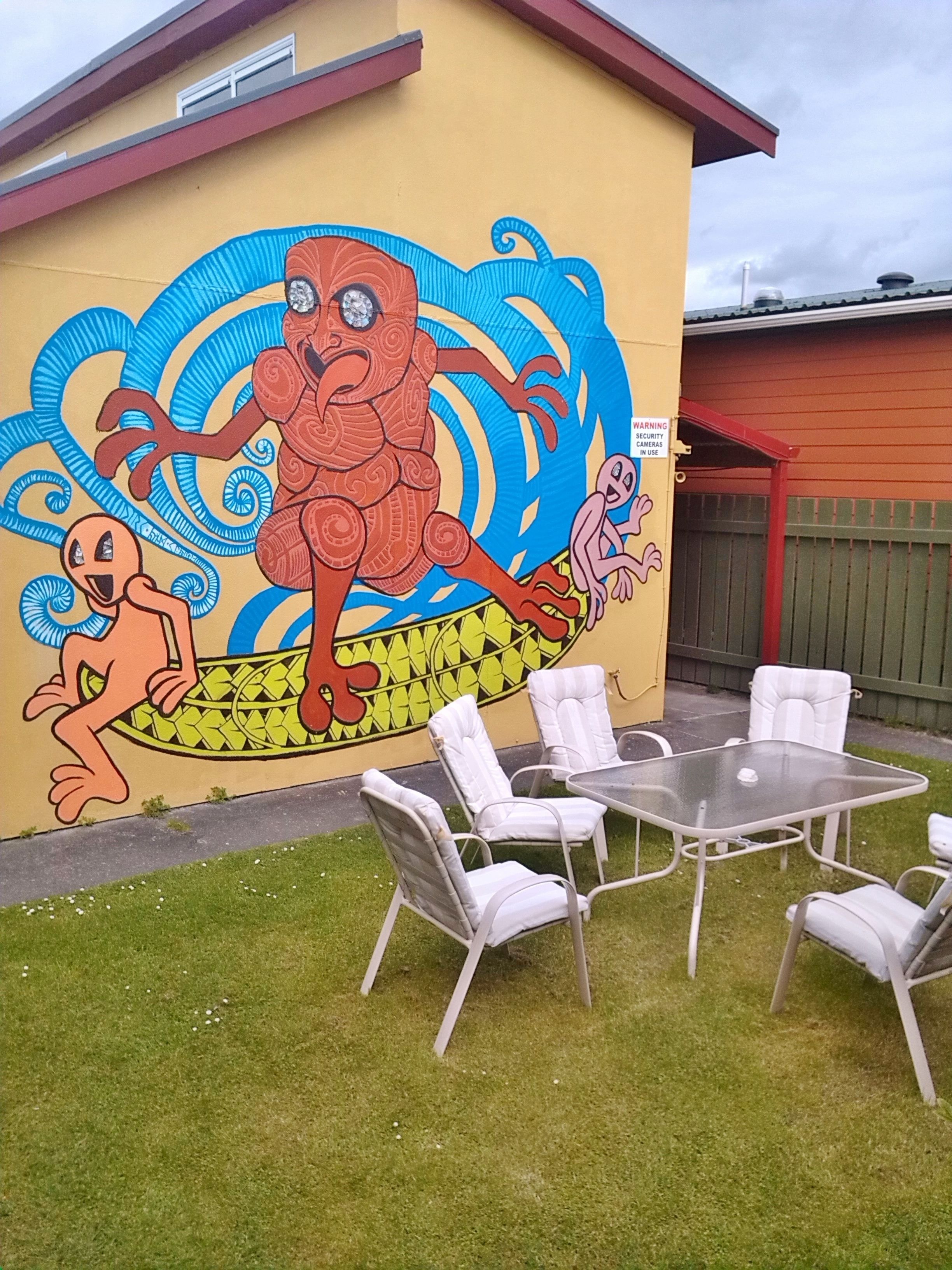A mural on a building with a table and chairs in the foreground.