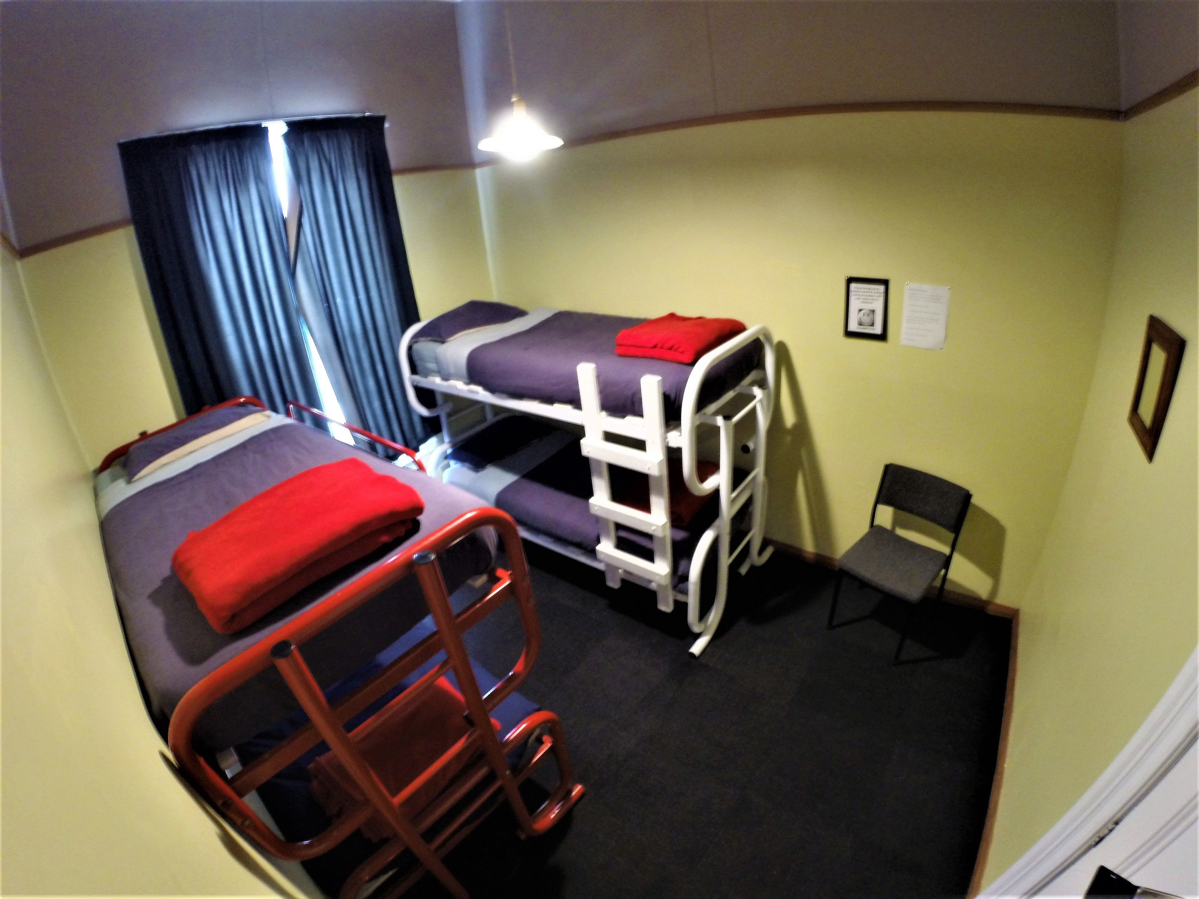 A room with two bunk beds, a chair, and a small table.