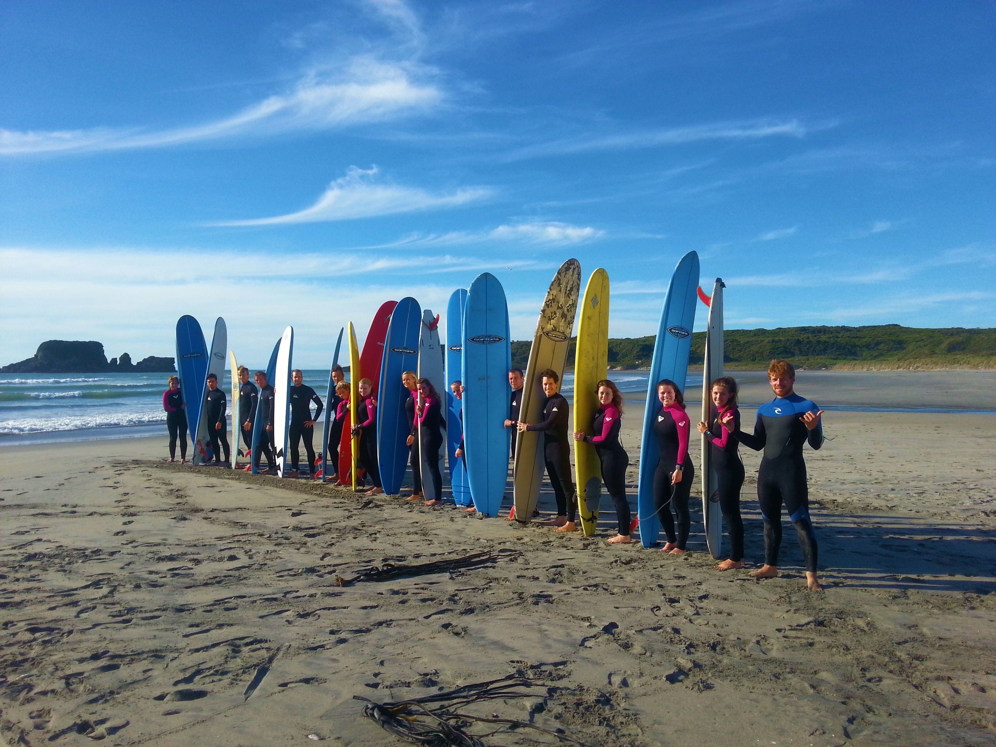 A group of people standing on a beach with surfboards lined up in a row.