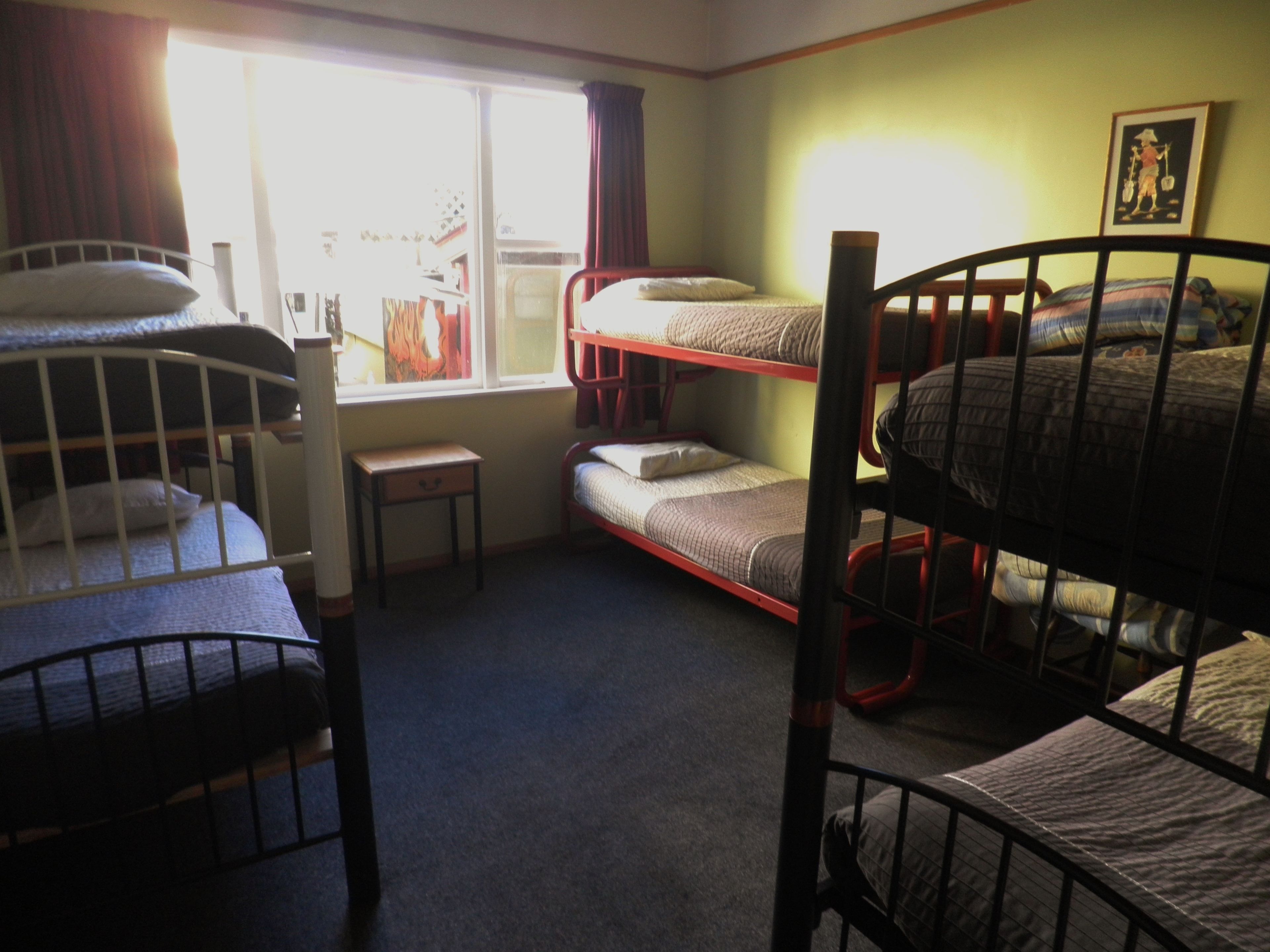 Un dormitorio con literas, un escritorio pequeño y una ventana con cortinas.