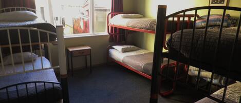 Un dormitorio con literas, un escritorio pequeño y una ventana con cortinas.