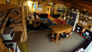 A cozy kitchen with a wooden table, a brick fireplace, and various kitchen utensils. - Bazil's Hostel & Surf School (Westport)