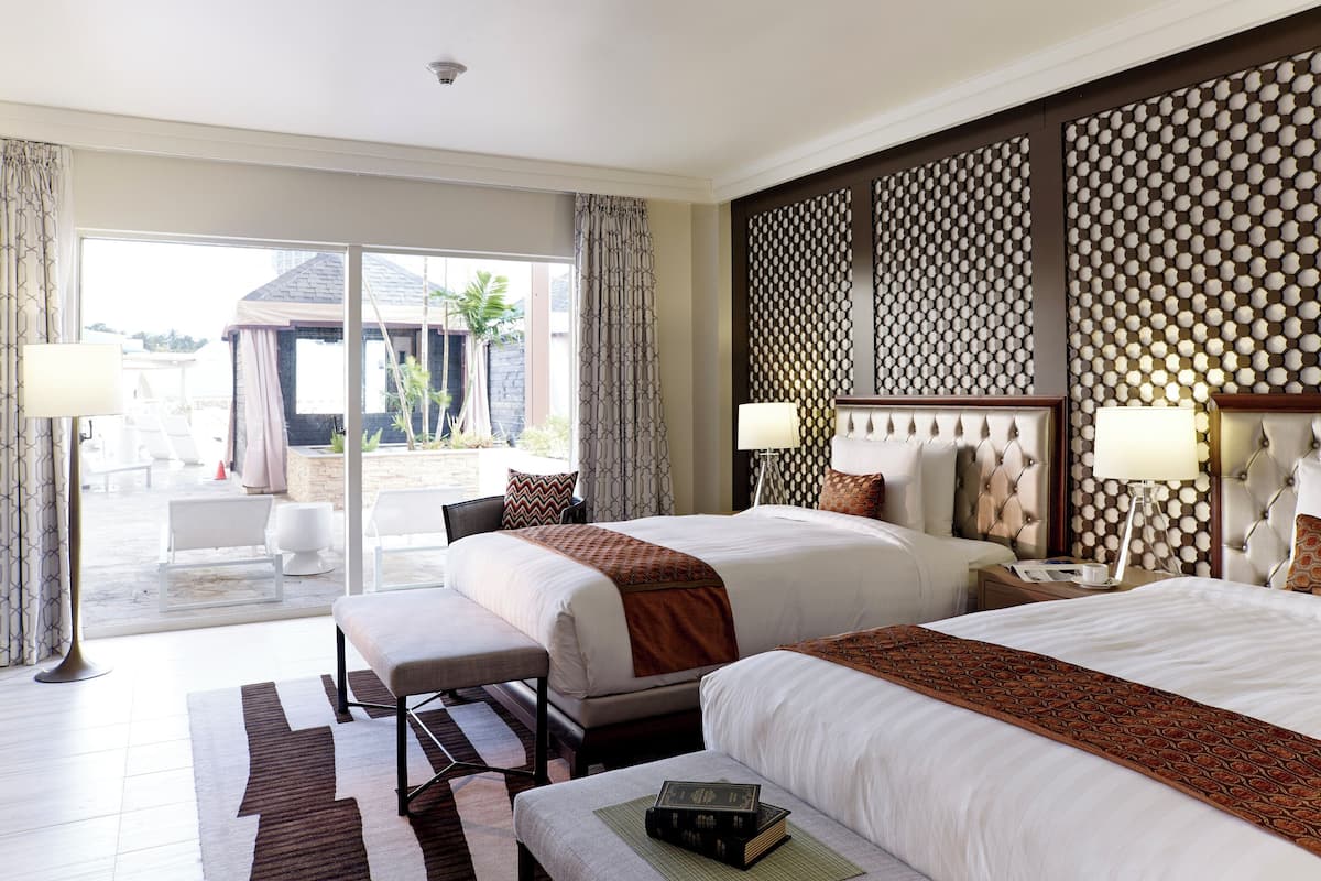 A hotel room with two beds, a large window, and a view of the outside.