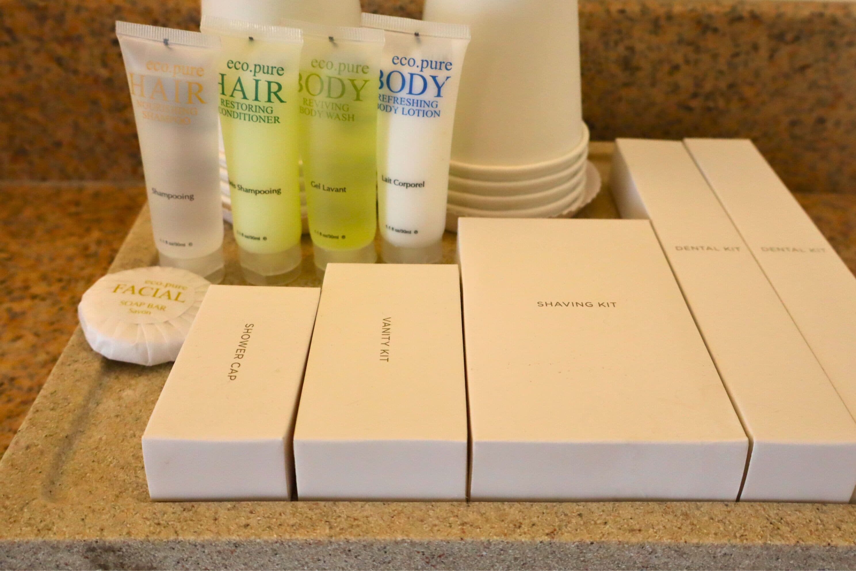 A bathroom counter with various personal care items including shampoo, body wash, lotion, and a shaving kit.