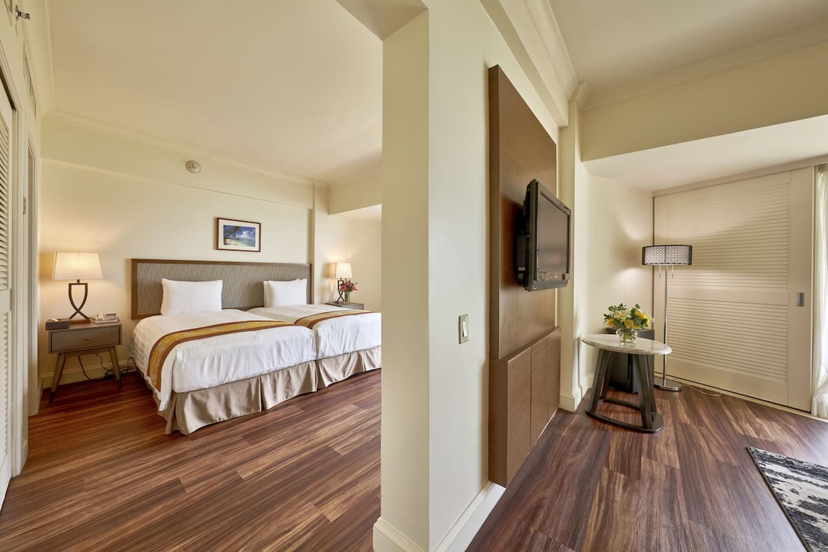 A hotel room with a double bed, bedside tables with lamps, a TV mounted on the wall, and a sliding door closet.
