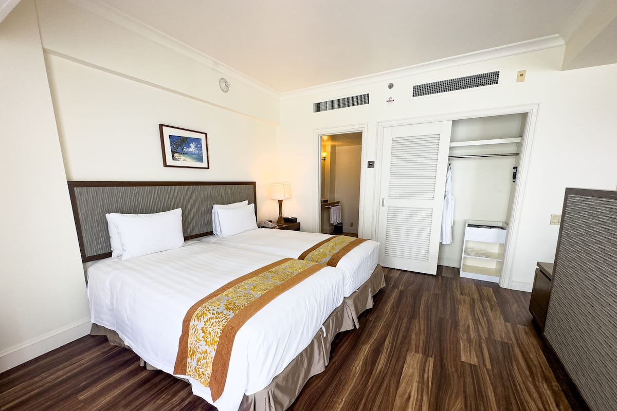 A hotel room with a large bed, a bedside table with a lamp, a wardrobe, and a mirror.